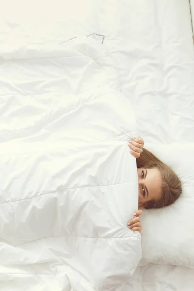 Cara primer plano de una hermosa mujer joven escondiendo su cara debajo de la sábana —  Fotos de Stock