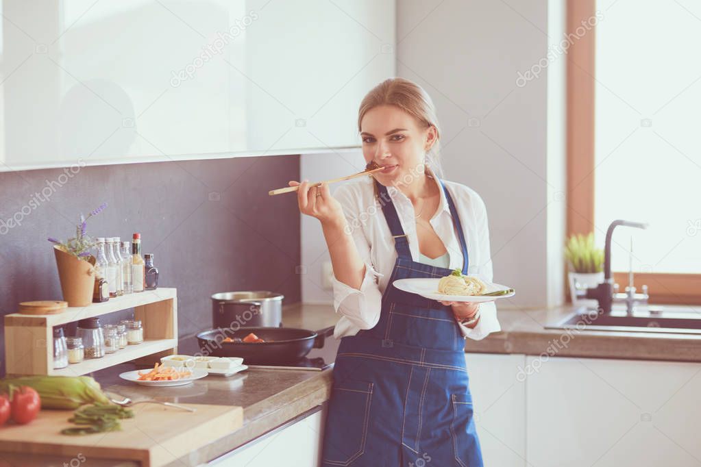 Young woman standing by the stove in the kitchen