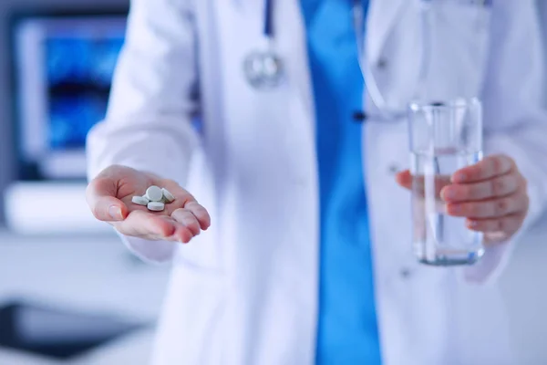 Lövés az orvosok kezét tartó tabletták és pohár víz a klinikán. — Stock Fotó