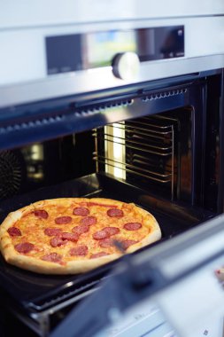 Mutlu genç bayan evde pizza pişiriyor.