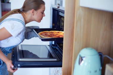Mutlu genç bayan evde pizza pişiriyor..