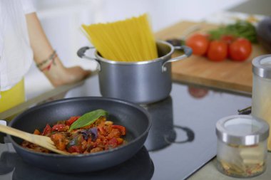 Mutfakta yemek hazırlayan genç bir kadın.