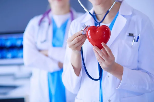 Ritagliato tiro di due giovani medici femmina con stetoscopio tenendo il cuore. — Foto Stock