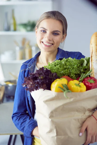 Young woman holding grocery shopping bag with vegetables .Standing in the kitchen — Stock Photo, Image