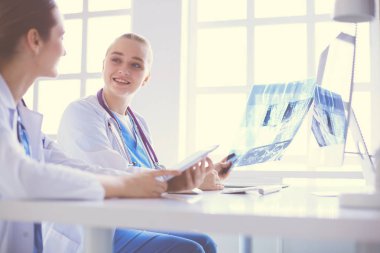 Kadın doktorlar hastanede röntgen görüntülerini inceliyor ve tartışıyorlar..