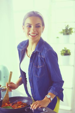 Mutfakta yemek hazırlayan genç bir kadın.