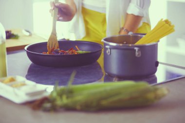 Mutfakta yemek hazırlayan genç bir kadın.