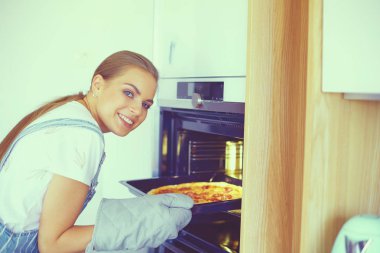 Mutlu genç bayan evde pizza pişiriyor.