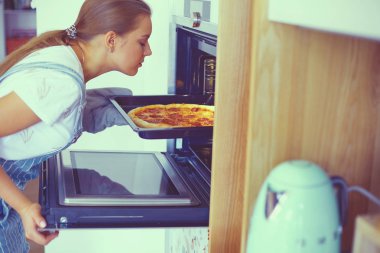 Mutlu genç bayan evde pizza pişiriyor.