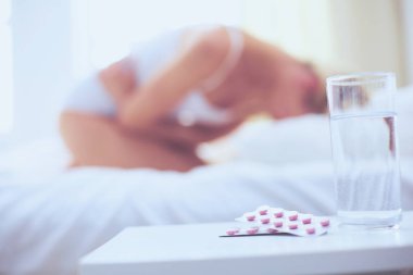 Genç, güzel bir kadın. Yatağında haplarla yatıyor.