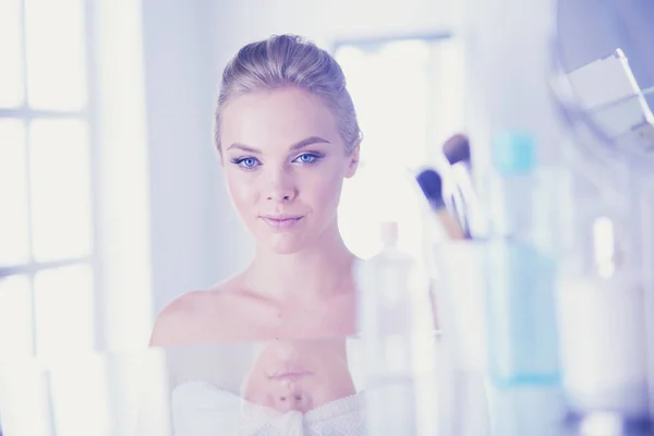 Giovane donna in accappatoio guardando nello specchio del bagno — Foto Stock