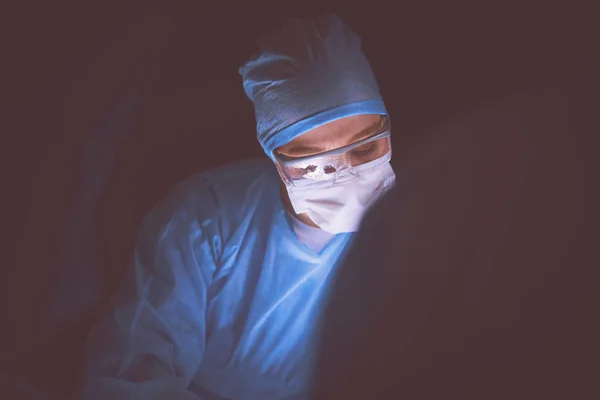 Doctor performing surgery in a dark background
