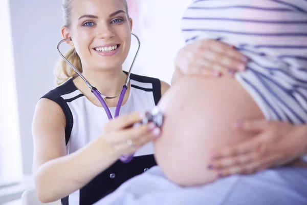 A fiatal női orvos portréja, amint terhes nőt vizsgál a klinikán. — Stock Fotó