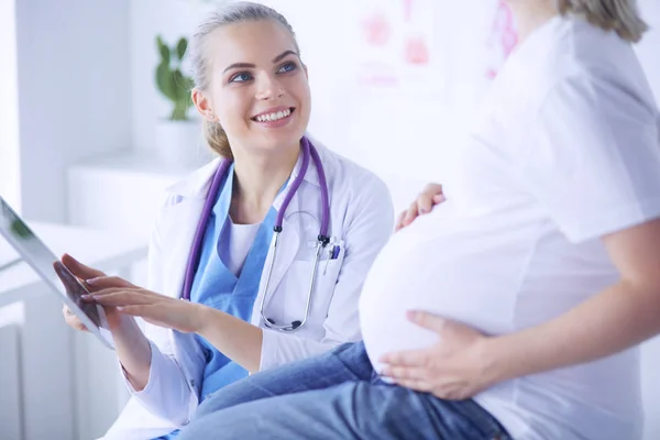 Il medico sorridente mostra le immagini sulla compressa a una giovane donna incinta in ospedale. — Foto Stock