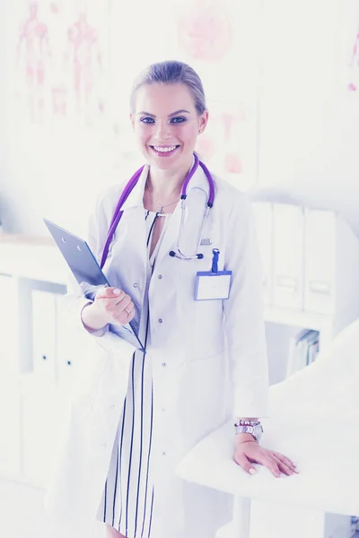Glimlachende vrouwelijke arts met een map in uniform staand — Stockfoto