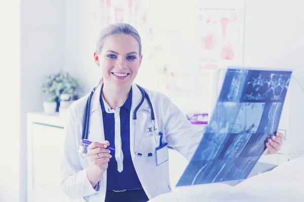 Νεαρή ελκυστική γυναίκα γιατρός κοιτάζοντας την εικόνα ακτίνων Χ — Φωτογραφία Αρχείου