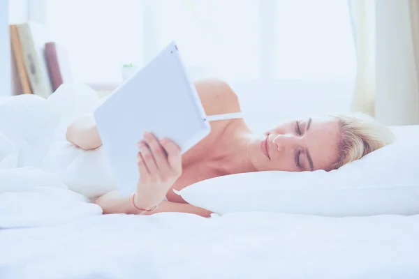 Menina segurando tablet digital com tela em branco e sorrindo para a câmera no quarto — Fotografia de Stock