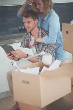 Genç bir çift yeni ev içinde hareket. Oturma ve açma sonra rahatlatıcı. Bir şey üstünde laptop arıyorum. Genç Çift