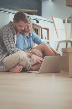 Genç bir çift yeni ev içinde hareket. Oturma ve açma sonra rahatlatıcı. Bir şey üstünde laptop arıyorum. Genç Çift
