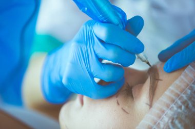 Kaşlar için kalıcı makyaj. Güzellik salonunda kalın kaşlı güzel bir kadın..