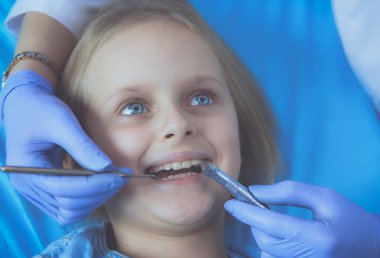 Küçük kız dişçi ofisinde oturuyor..