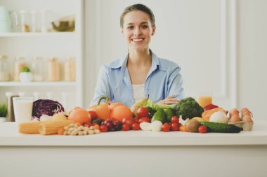 Ahşap iç kısımda meyve ve sebze dolu masada oturan genç ve tatlı bir kadın..
