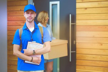Mavi üniformalı gülümseyen kurye servis konseptine paket kutusu teslim eden teslimatçı. Mavi üniformalı gülümseyen teslimatçı.