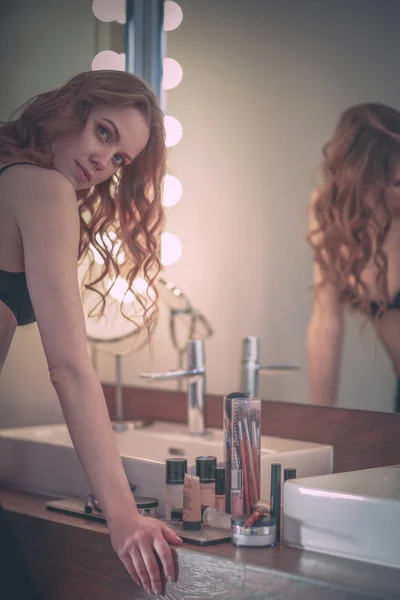 浴室の鏡で自分自身を見ている若い女性. — ストック写真