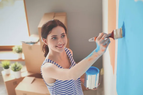 Щаслива усміхнена жінка малює внутрішню стіну нового будинку. Щаслива усміхнена жінка — стокове фото