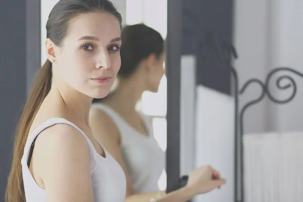 Jonge vrouw zichzelf reflectie in spiegel thuis kijken. — Stockfoto