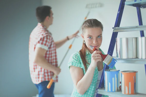 Portrait happy smiling young couple painting interior wall of new house. Young couple — Stock Photo, Image