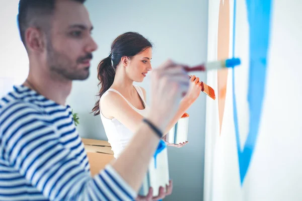 Portrait of happy smiling young couple painting interior wall of new house. young couple — Stock Photo, Image