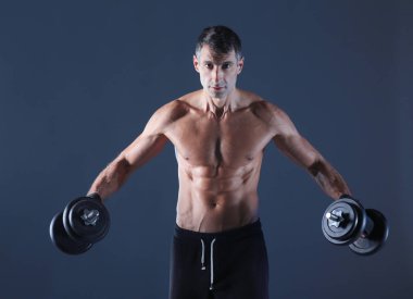 Yakışıklı kaslı adam dumbell ile çalışma dışarı. Kişisel fitness eğitmeni. Kişisel eğitim.