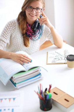 Kitapların arasında bir masada oturan genç bir kadın. Öğrenci