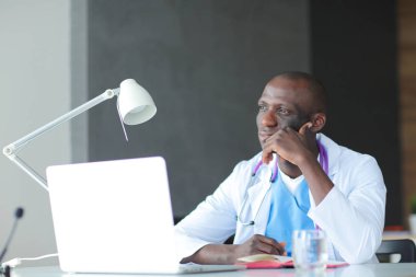 Masada dizüstü bilgisayarla çalışan genç bir Afrikalı doktor. Doktor bey. İşyeri