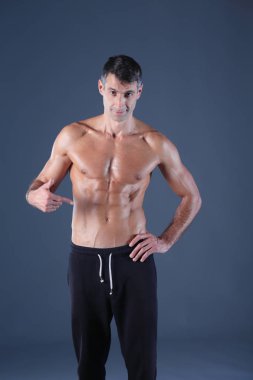 kaslı adam. Kaslı adam kas gösterilen gri arka plan üzerinde. Fitness Eğitmeni. Fitness profesyonel. Egzersiz. Mens fitness.