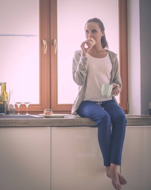 Mutfakta dijital tablet kullanan güzel genç bir kadın..