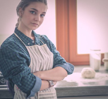 Mutfakta sobanın yanında duran genç bir kadın. .