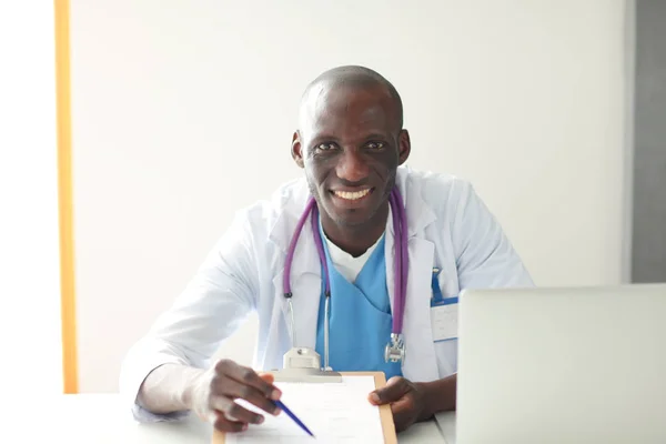 Porträtt av ung manlig läkare bär headset när du använder datorn vid skrivbordet på kliniken. Läkare. — Stockfoto