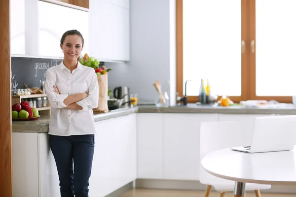 Портрет молодой женщины, стоящей со скрещенными руками на кухонном фоне. Женщина на кухне . — стоковое фото