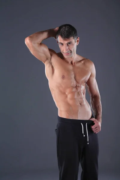 Musclé. Homme musclé sur fond gris montrant des muscles. Professeur de fitness. Professionnel de fitness. Entraînement. Fitness homme . — Photo
