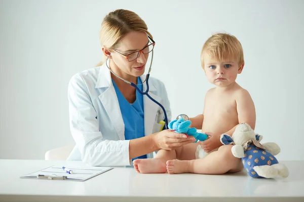 Vrouwelijke arts luistert kind met een stethoscoop in de kliniek — Stockfoto