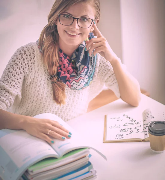 Jonge vrouw zit achter een bureau tussen de boeken. Studenten — Stockfoto