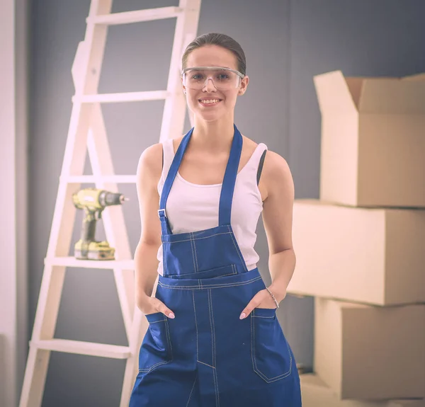 Feliz bela jovem fazendo pintura de parede, de pé perto escada — Fotografia de Stock