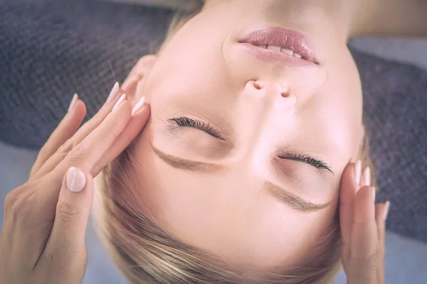 Mujer joven acostada en una mesa de masaje, relajándose con los ojos cerrados. Una mujer. Salón de spa — Foto de Stock