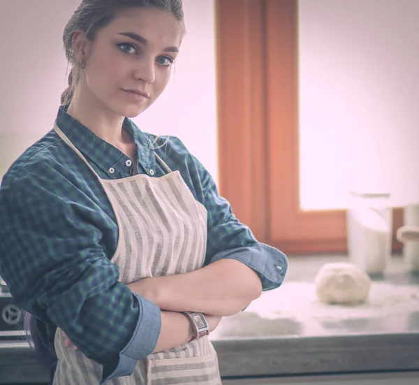 Ung kvinna står vid spisen i köket . — Stockfoto
