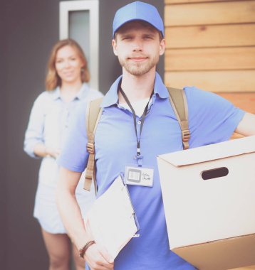 Mavi üniformalı gülümseyen kurye servis konseptine paket kutusu teslim eden teslimatçı. Mavi üniformalı gülümseyen teslimatçı.