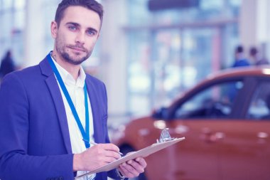Satıcı yeni bir araba showroom yakın duruyor.