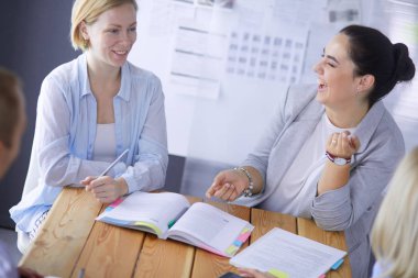 Masada kitaplarla çalışan gençler. Güzel kadınlar ve erkekler birlikte çalışıyor..