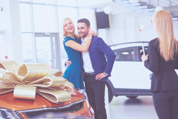 Een man maakt een geschenk - een auto aan zijn vrouw. Ze is hier verbaasd over. Ze zijn hier erg blij mee. — Stockfoto